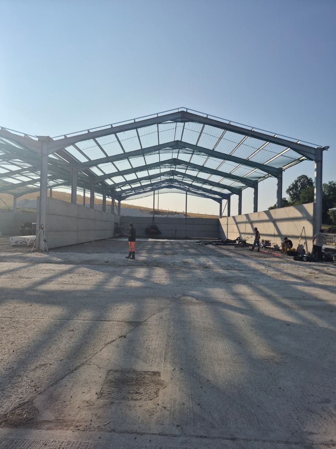 Crew setting out levels inside an open steel barn frame