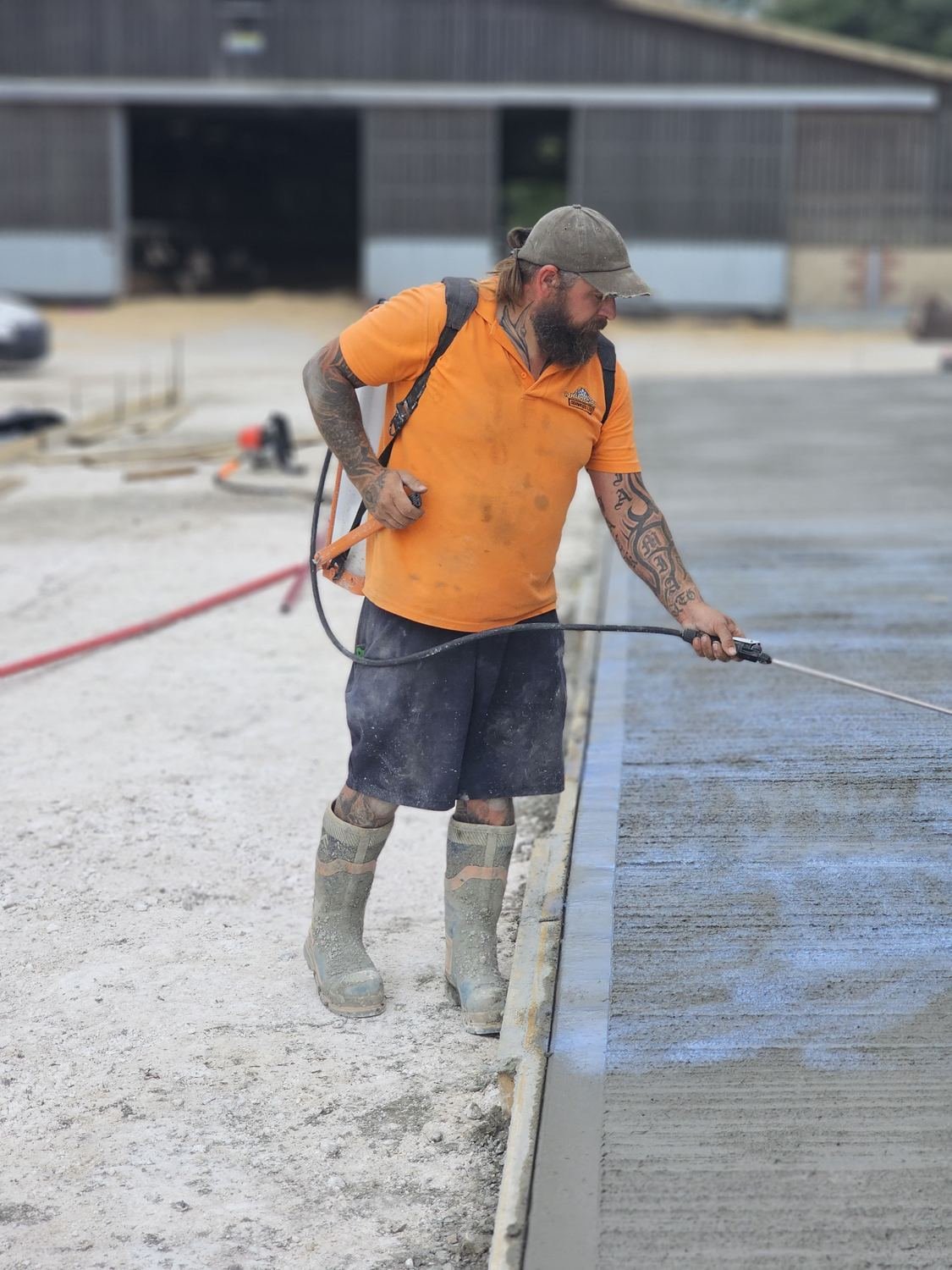 Operator spraying curing compound onto a fresh slab