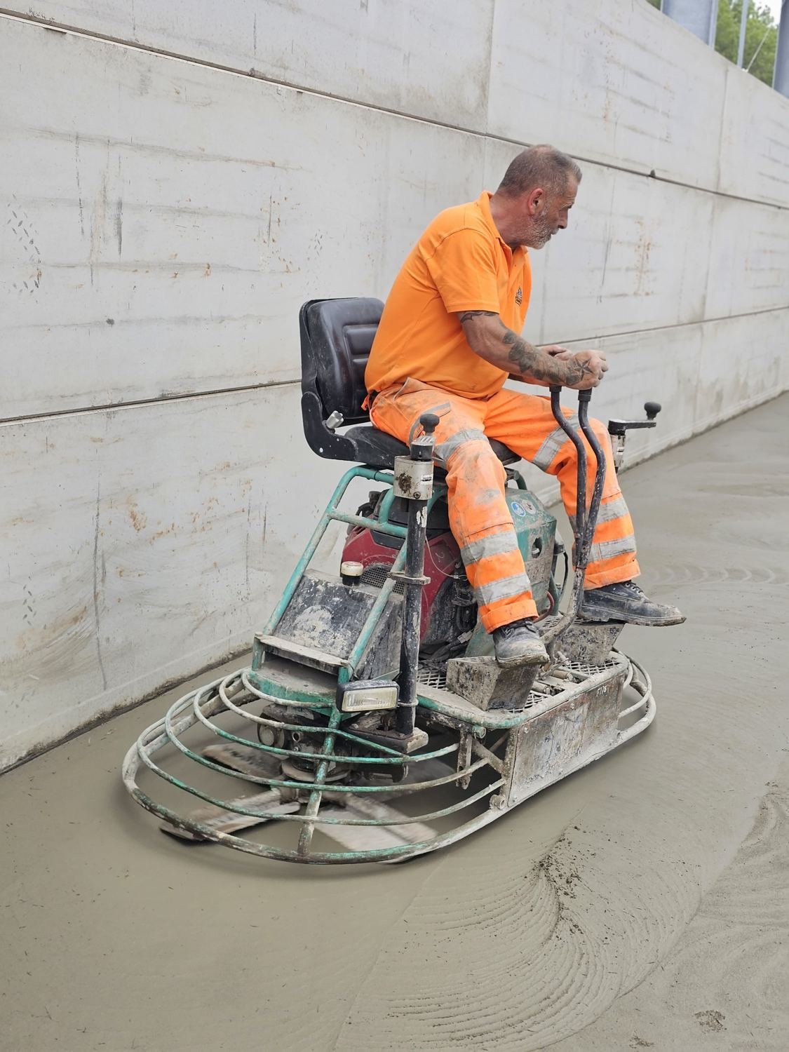 Second ride-on power trowel working along a wall